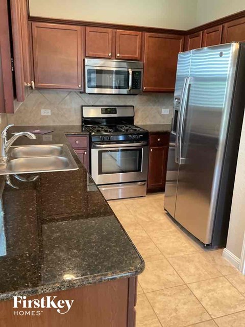 A kitchen with a stove, refrigerator, and microwave.