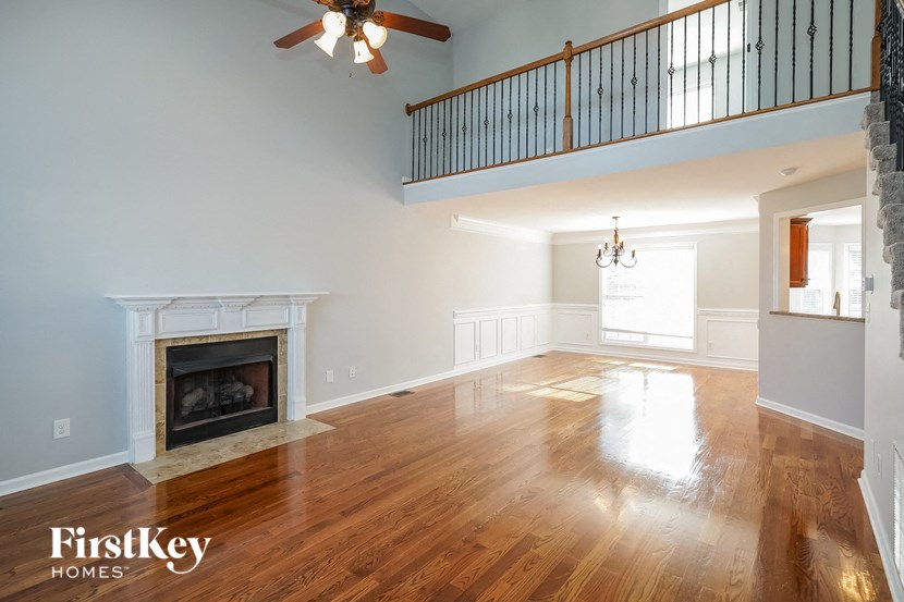 an empty living room with a fireplace and a ceiling fan
