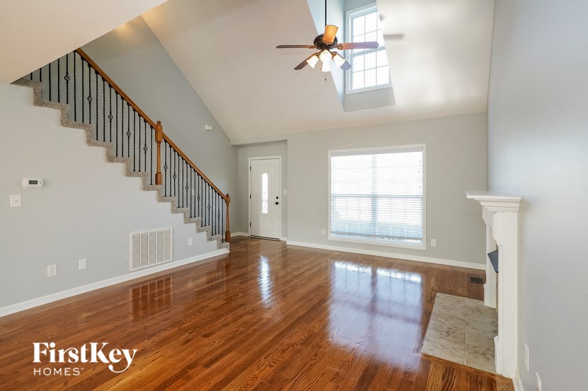 an empty living room with a ceiling fan and a window