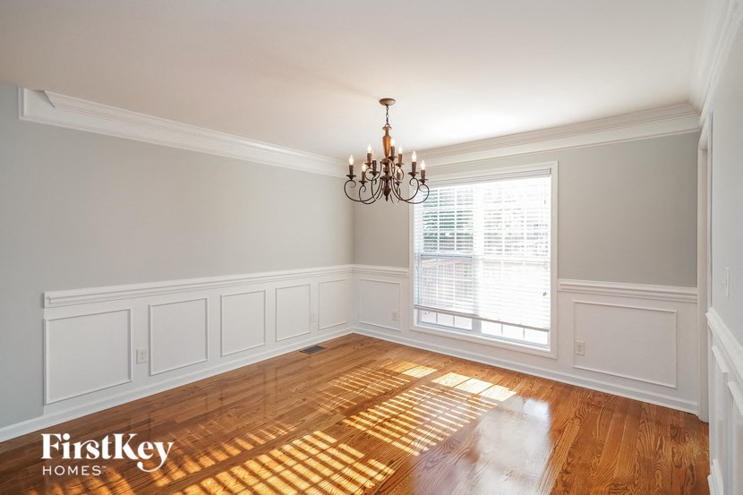 an empty dining room with a chandelier and a window