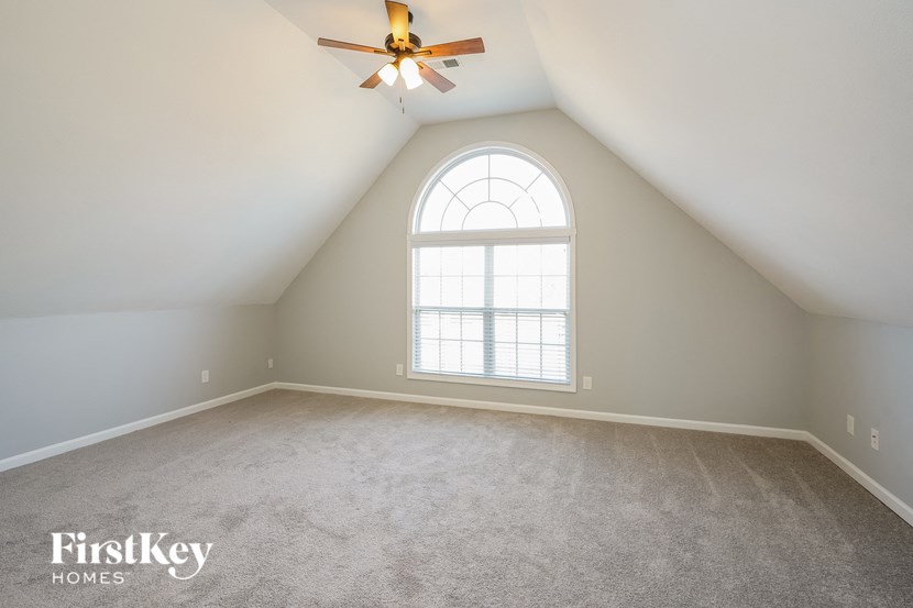 an empty attic with a large window and a ceiling fan