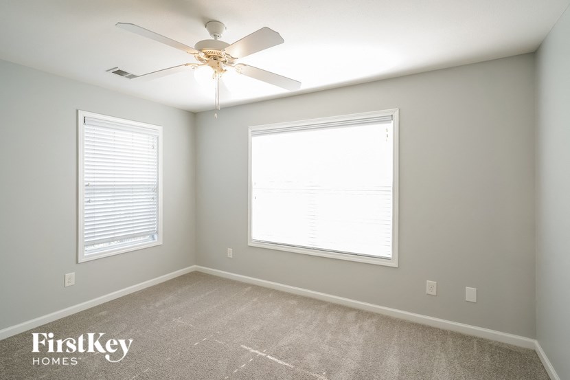 a bedroom with a ceiling fan and two windows