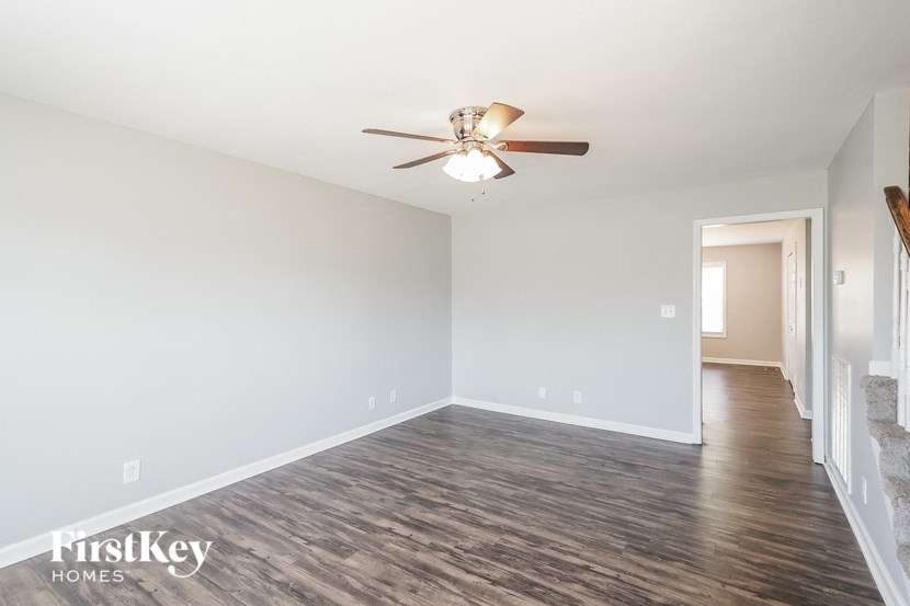 an empty living room with a ceiling fan and wood flooring