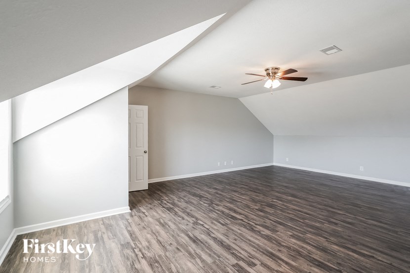 the attic of a home with white walls and a ceiling fan