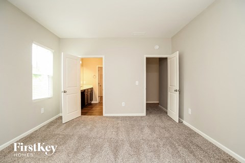 a master bedroom with carpet and a door to a bathroom