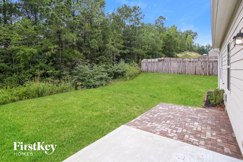 a backyard with a grass lawn and a wooden fence
