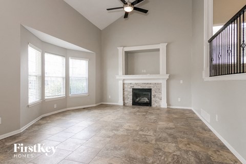 an empty living room with a fireplace and a ceiling fan