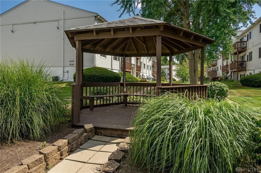 A gazebo in a garden with a building in the background.