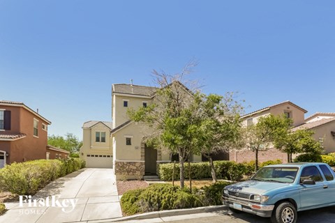 A blue car is parked in front of a house with the sign "Firstkey HOMES" on the bottom left.
