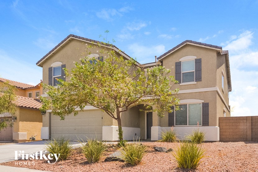 A beige house with a tree in front of it.