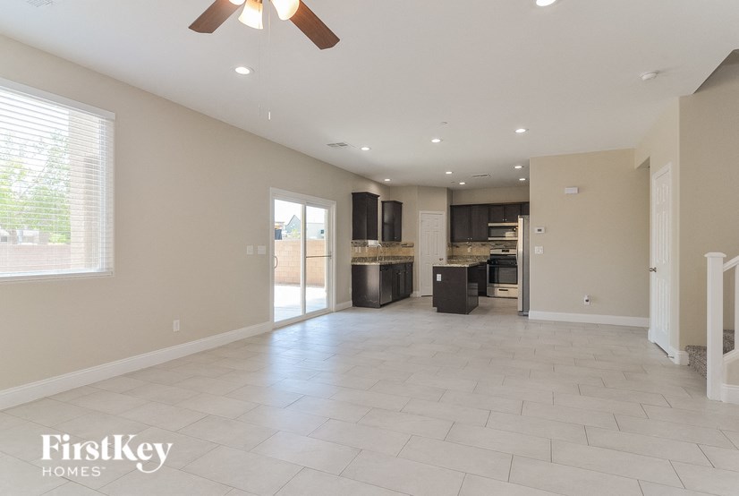 A spacious living room with a ceiling fan and tiled flooring.