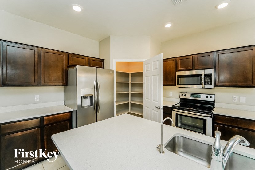 A kitchen with a refrigerator, microwave, oven, and sink.
