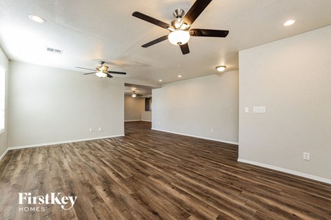 A room with a ceiling fan and wooden flooring.