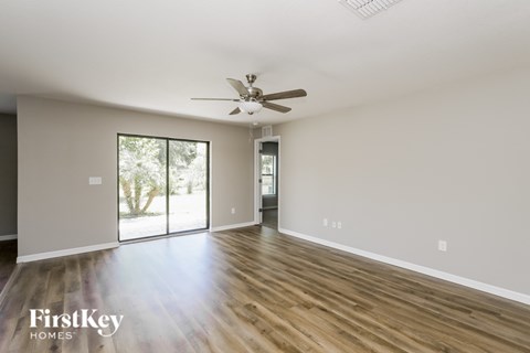 A spacious room with a ceiling fan and sliding glass doors leading to a patio.