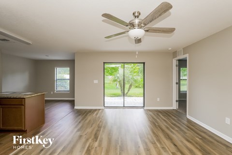A spacious room with a ceiling fan and wooden flooring.