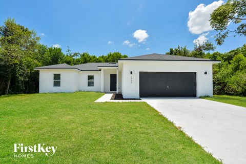 A white house with a black garage door is for sale by FirstKey Homes.