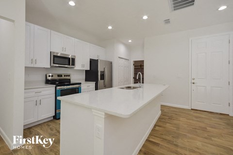 A kitchen with white cabinets and a white island.