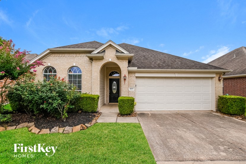 a beige brick house with a white garage door