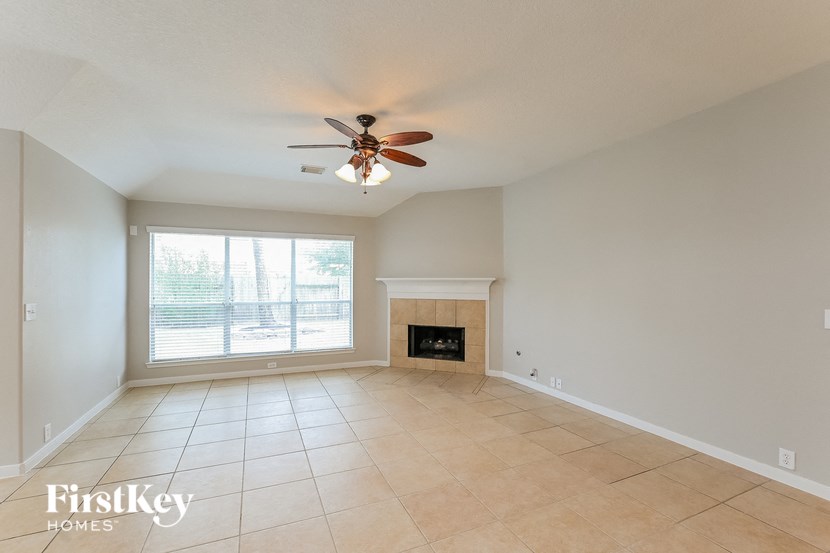an empty living room with a ceiling fan and a fireplace
