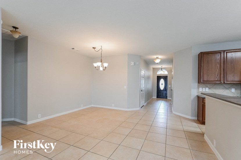 an empty kitchen and hallway with tile flooring and wooden cabinets