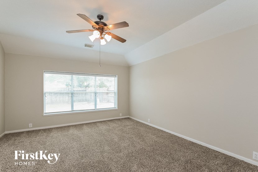 an empty bedroom with a ceiling fan and a window