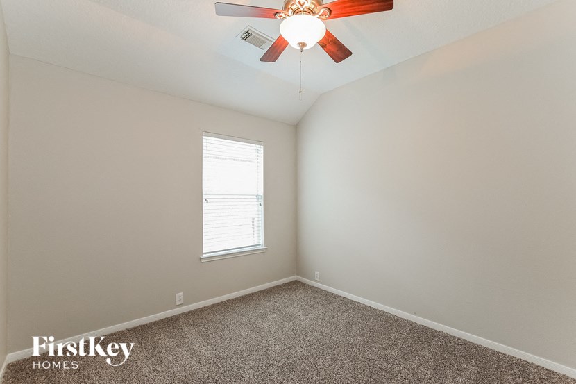 an empty bedroom with a ceiling fan and a window