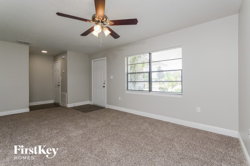 A spacious room with a ceiling fan and carpeted floor.