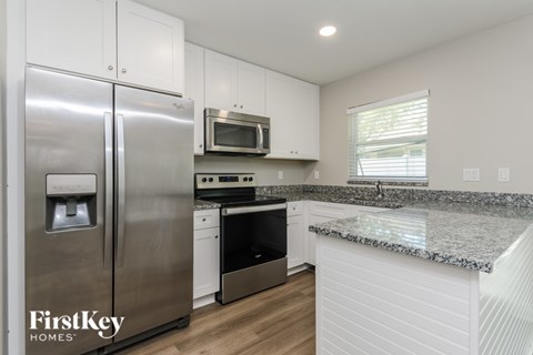 A kitchen with a stainless steel refrigerator and a granite countertop.