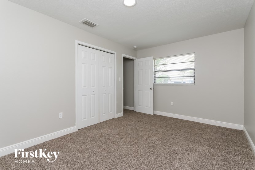 A room with a carpeted floor and a window with blinds.