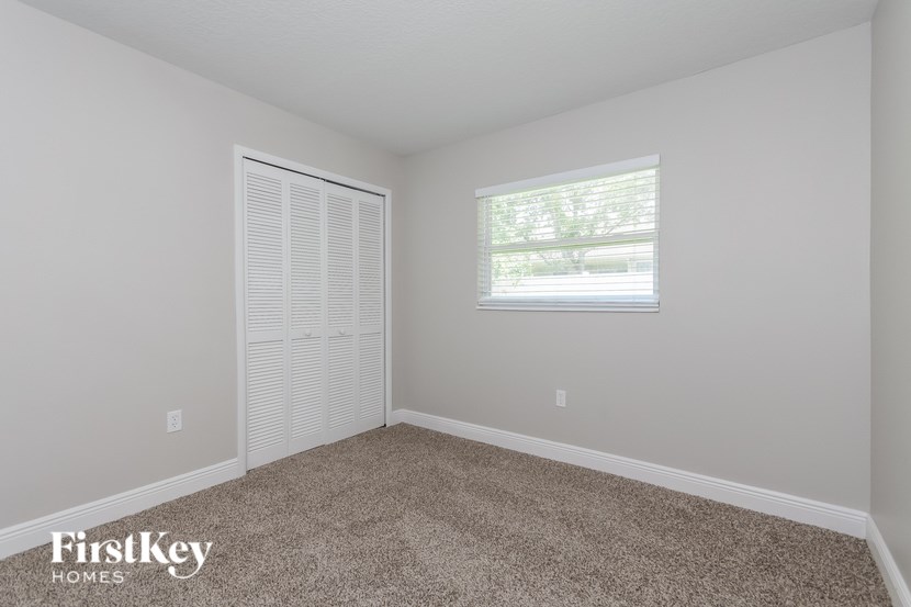 A room with a carpeted floor and a window with blinds.