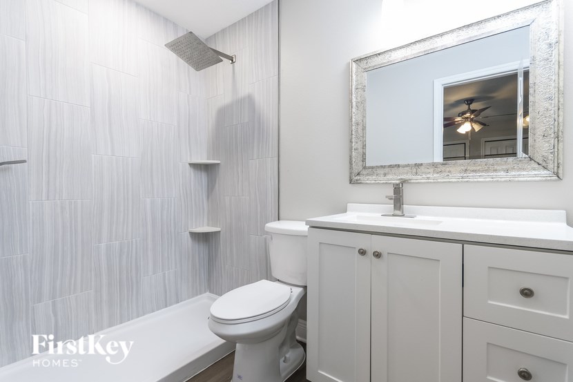 A white bathroom with a toilet, sink, and mirror.