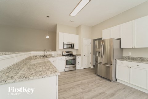 a kitchen with white cabinets and granite counter tops and stainless steel appliances