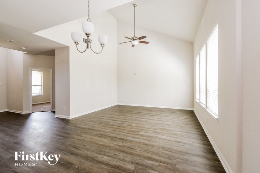 an empty living room with white walls and a ceiling fan