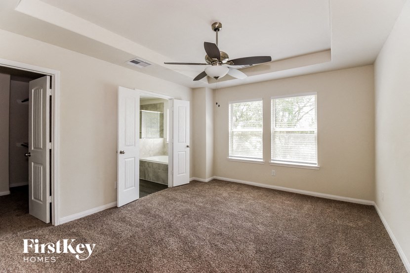 an empty living room with a ceiling fan and a door to a bathroom