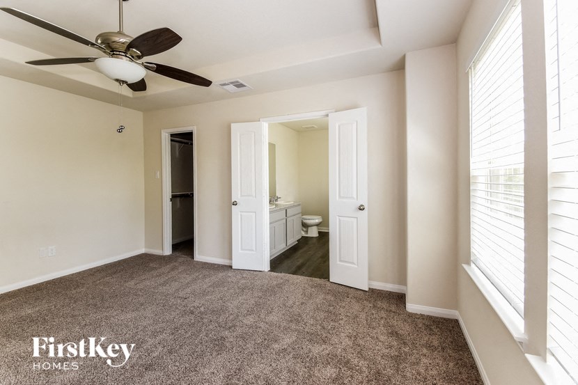 an empty living room with a ceiling fan and a bathroom