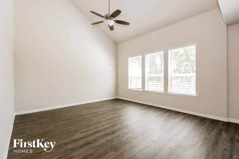 an empty living room with wood floors and a ceiling fan