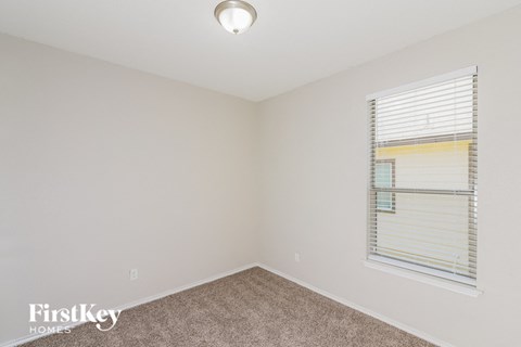 a bedroom with a window and a carpeted floor