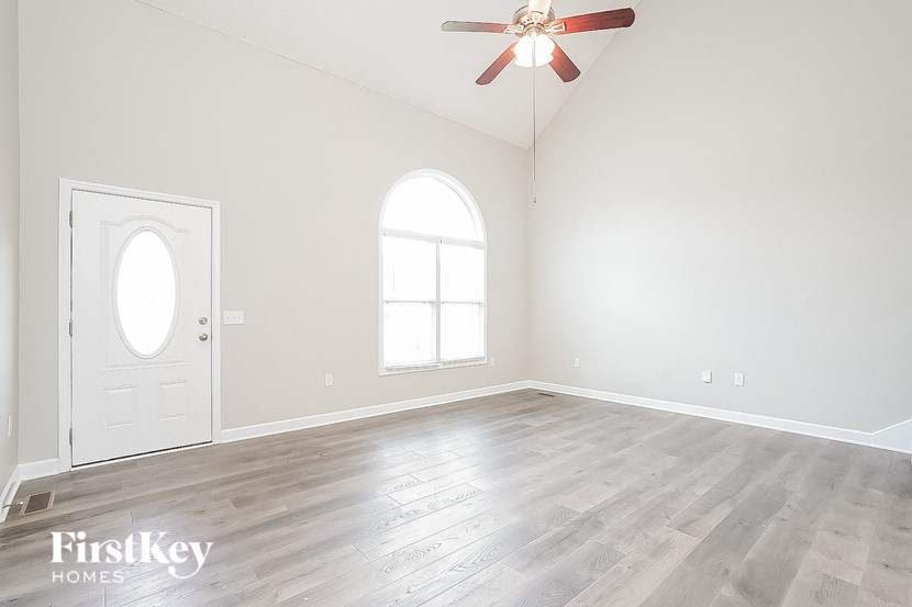 an empty living room with white walls and a ceiling fan