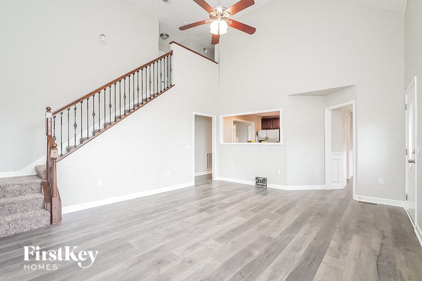 an empty living room with a ceiling fan and a staircase