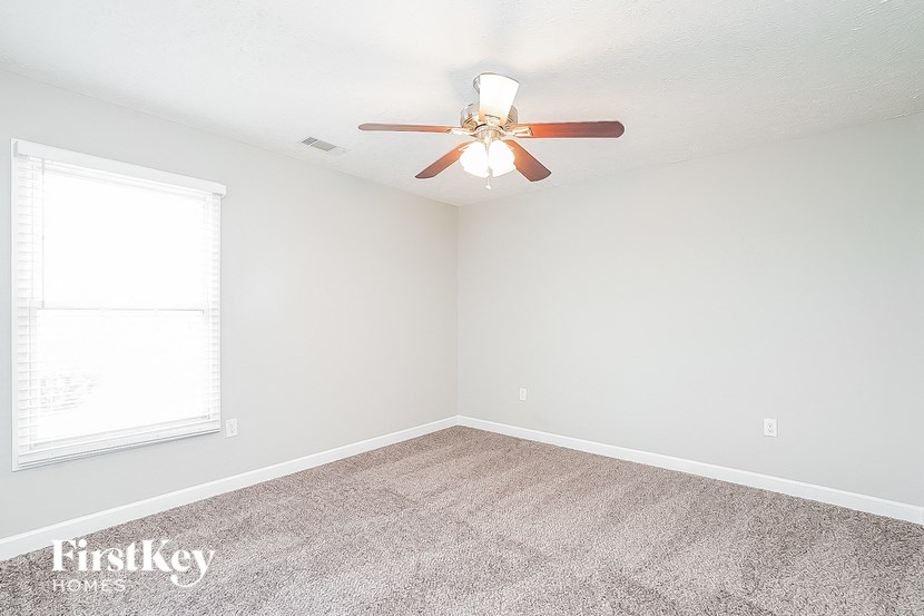 an empty room with a ceiling fan and a window