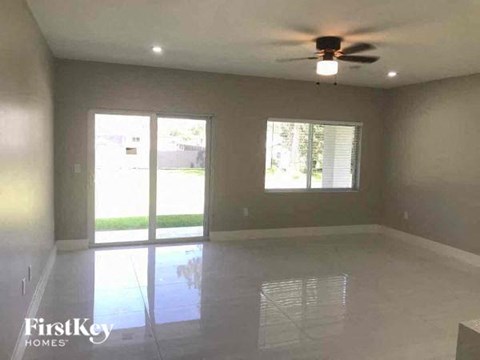 an empty living room with a ceiling fan and a window