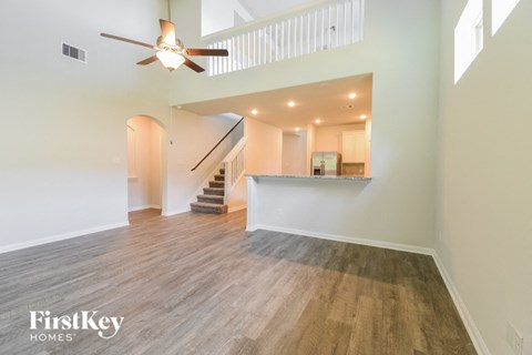 A spacious room with wooden flooring and a ceiling fan.