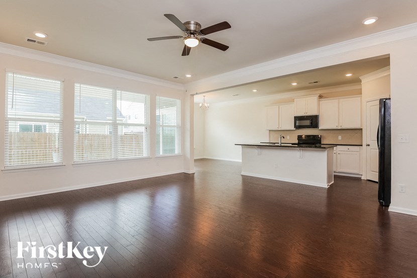 an empty living room and kitchen with a ceiling fan