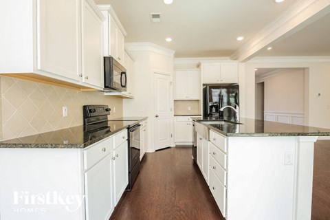 a large kitchen with white cabinets and black counter tops