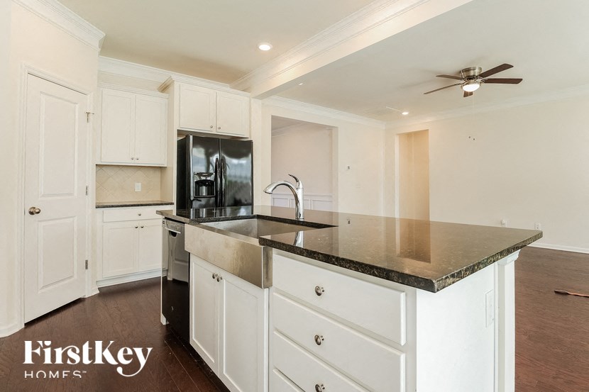 a kitchen with white cabinets and a black counter top