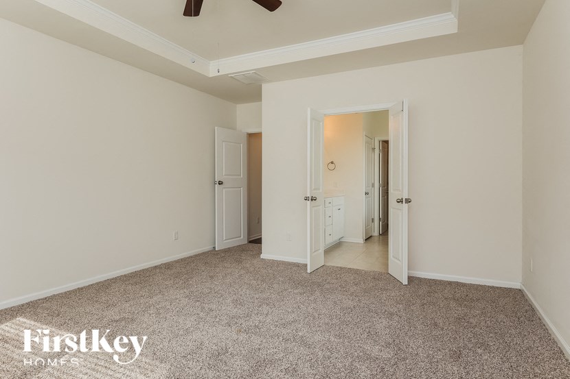 a master bedroom with a carpeted floor and a door to the bathroom