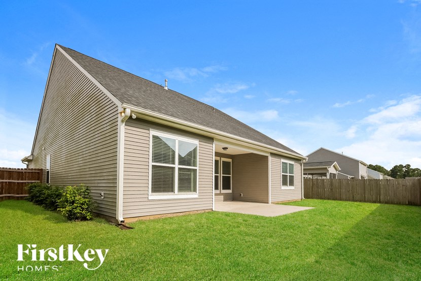 a small brown house with a yard and a fence