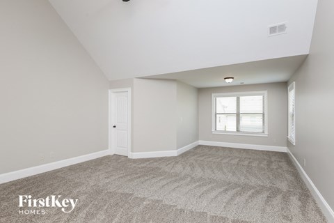 the living room of a new home with carpet and a window