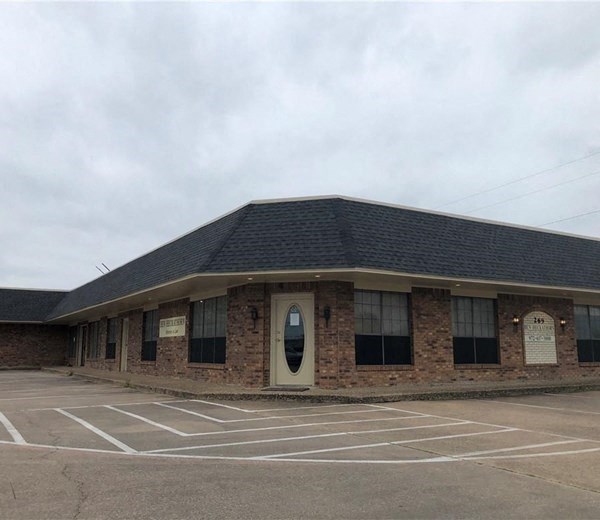 a brick building with a door in a parking lot