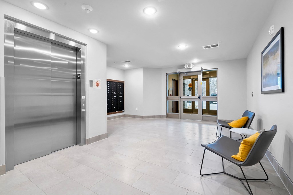 a large empty room with two chairs and a stainless steel refrigerator